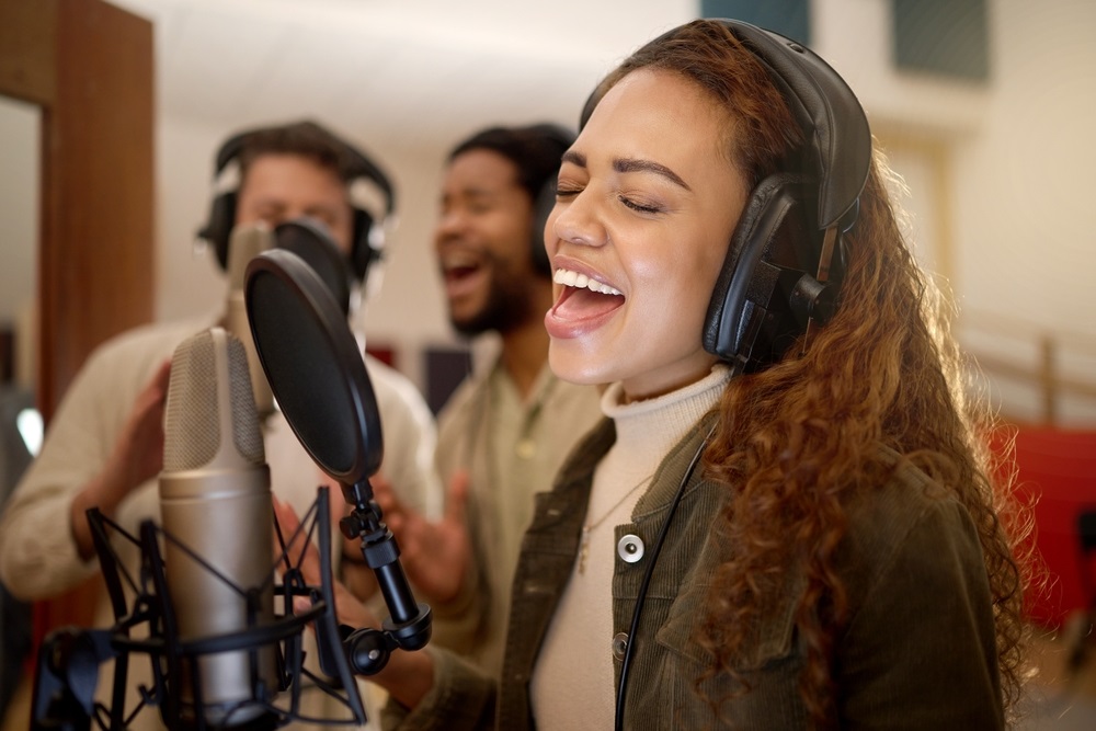 A person performing on stage behind a lead vocalist, representing the journey of how to become a backup singer.