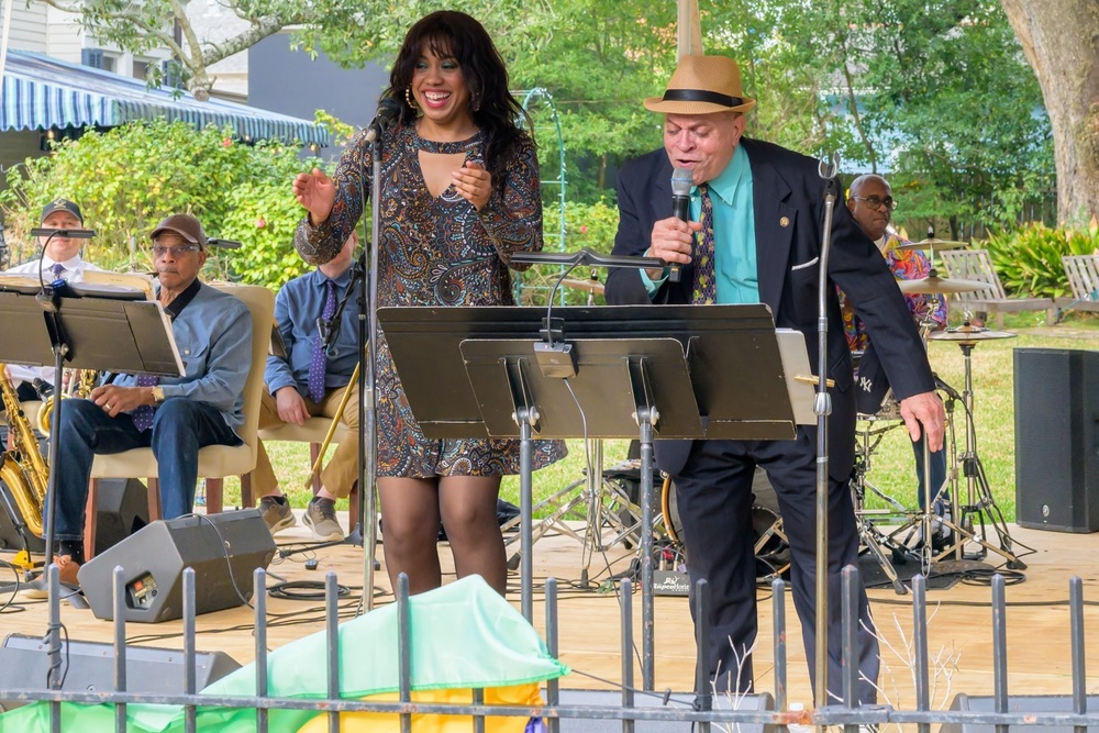 A person performing on stage behind a lead vocalist, representing the journey of how to become a backup singer.