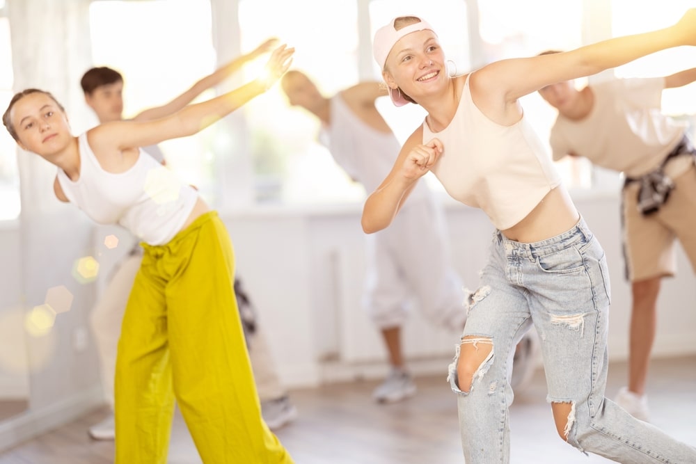 Dancers rehearsing in a professional dance studio with mirrored walls.