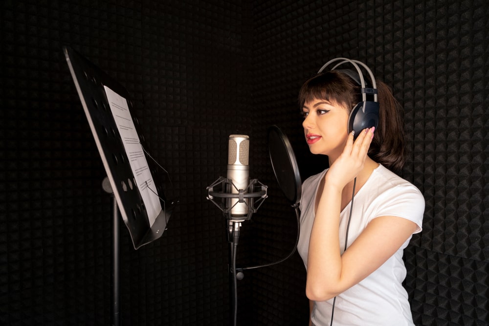 A teenage girl recording her voice for a voice acting job in a home studio.