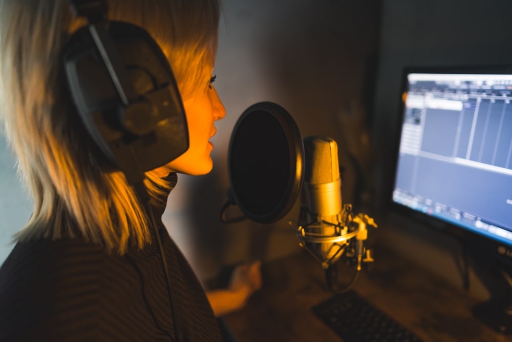 A teenage girl recording her voice for a voice acting job in a home studio.