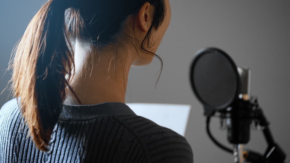 Commercial voice actor recording a script in a home studio